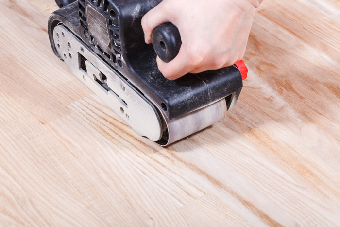 person using sanding tool on wooden floor