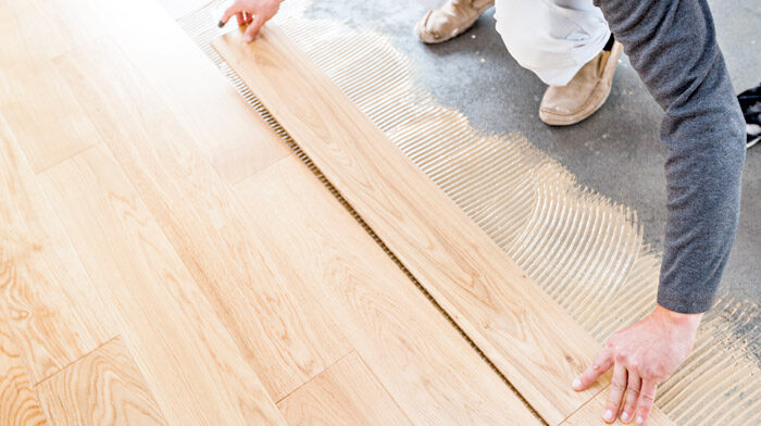 man laying wooden planks on concrete